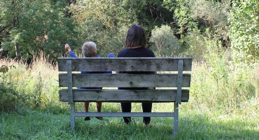 adult and child sitting on park bench