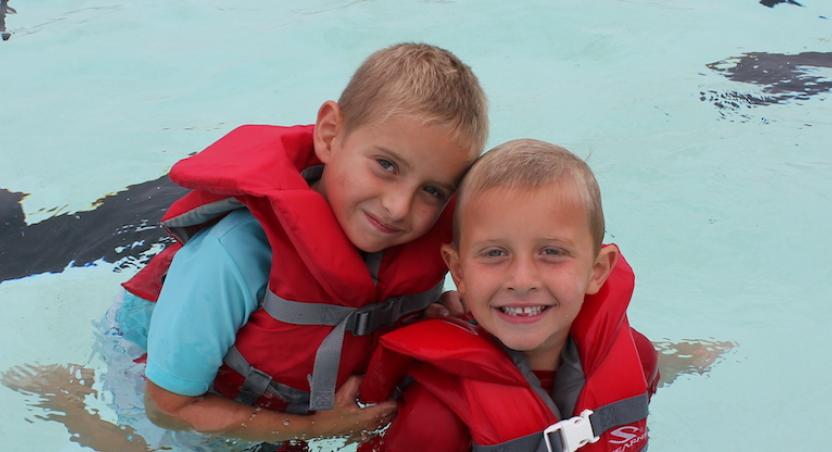 2 kids in pool with lifejackets